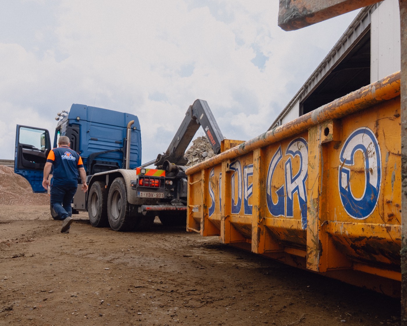 Sidegro-chauffeur naast een oranje container