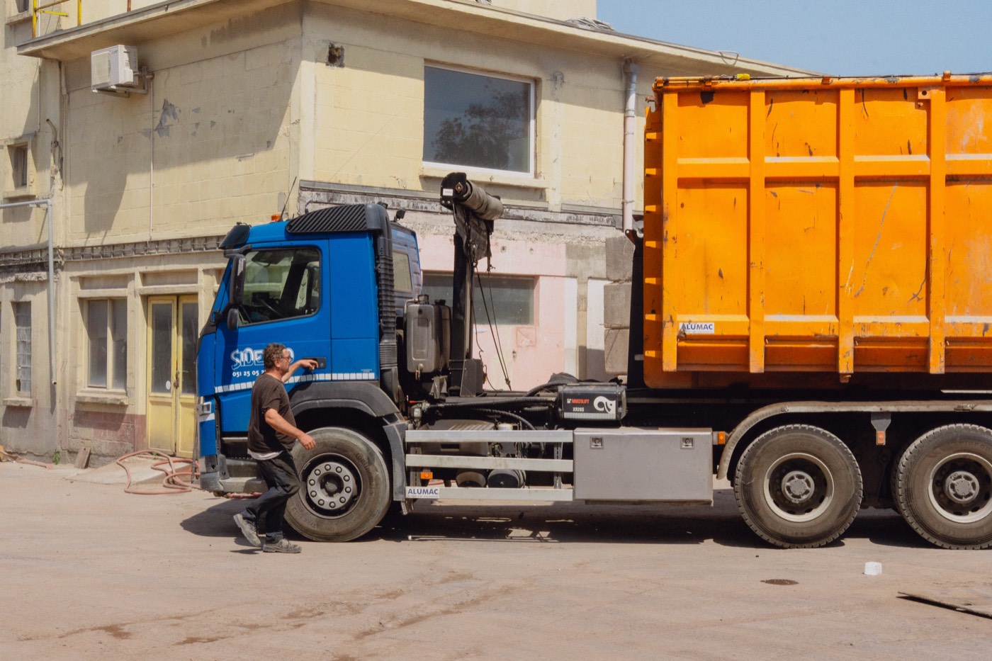 Sidegro-vrachtwagen haalt een oranje container op